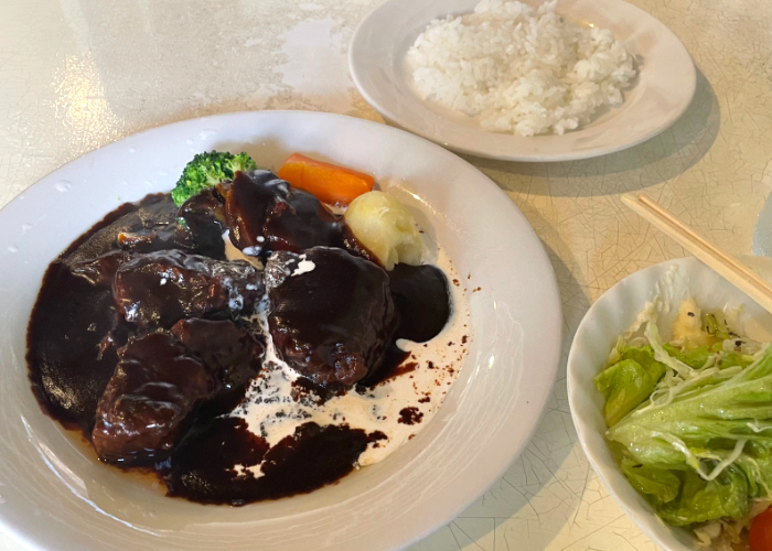 A plate of BUN Kichi Beef Stew, rice, and a salad